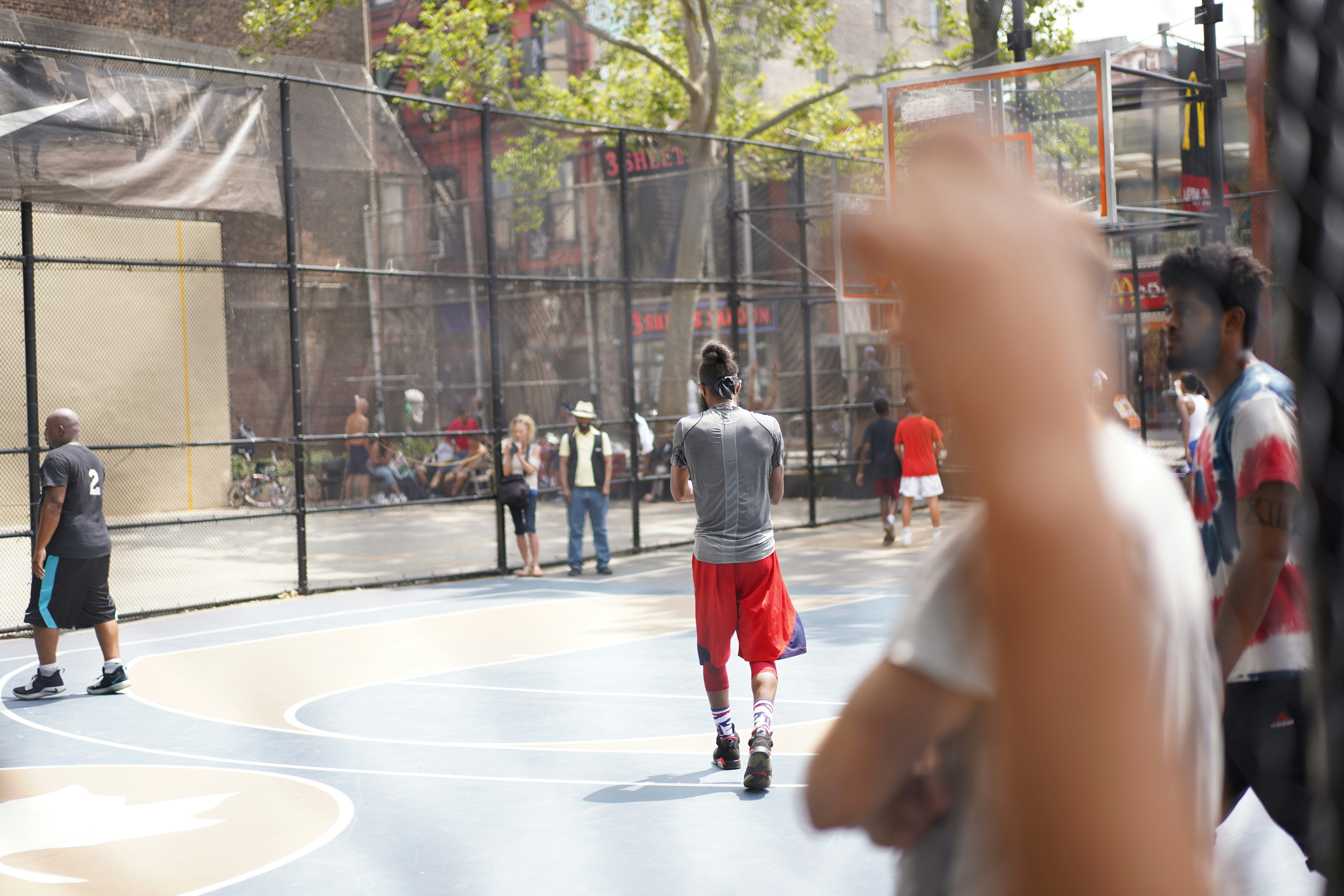 man in gray hoodie walking on white and black basketball court during daytime